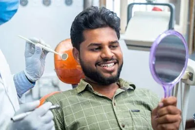 man smiling in the mirror after getting dental care from Brite Dental Partners