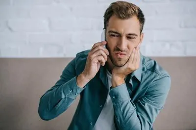 man with tooth pain scheduling an emergency dental appointment